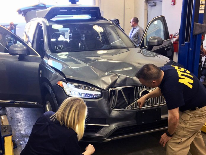 Handout photo of NTSB investigators examining a self-driving Uber vehicle involved in a fatal accident in Tempe